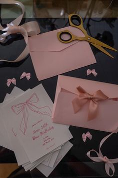 some cards and scissors on a table with pink bows, ribbons and ribbones around them