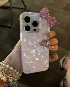 a person holding up a pink phone case with bows and glitters on the back