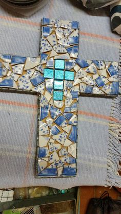 a blue and white mosaic cross sitting on top of a table next to other items