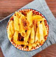 a bowl filled with pasta on top of a wooden table