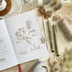 an open notebook on top of a table covered in crafting supplies