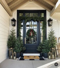 the front door is decorated with christmas wreaths and evergreen trees