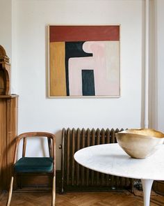 a bowl sitting on top of a white table next to a wooden chair and radiator