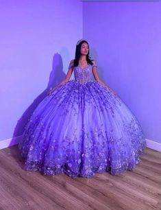 a woman in a purple ball gown standing next to a wall