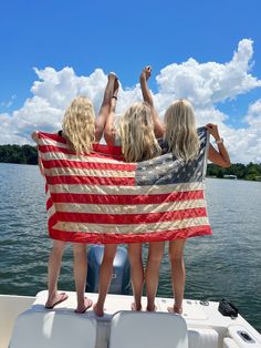 three women on a boat with an american flag draped over their shoulders and hands in the air