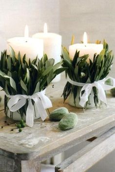 candles wrapped with greenes are sitting on a table