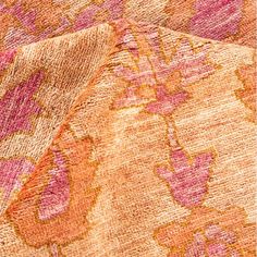 an orange, pink and yellow rug with flowers on the bottom half is shown in close up