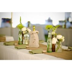 several vases filled with flowers sitting on top of a white table cloth covered table