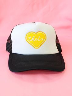 a white and black trucker hat with a yellow heart on the front that says fiesta