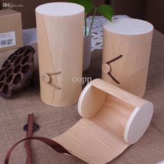 three wooden vases sitting on top of a table next to a plant and ribbon