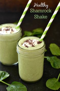 two glasses filled with green smoothie and topped with whipped cream