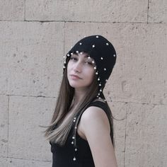 a woman with long hair wearing a black hat and pearls on it's head