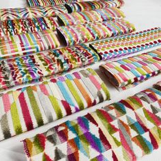 colorful towels laid out on top of each other in different colors and patterns, with one rolled up to the side