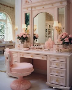 a pink vanity with flowers in vases on it and a chair next to it