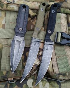 three knives sitting on top of a camouflage bag