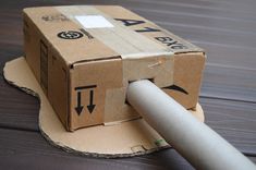 a cardboard box sitting on top of a wooden table next to a white plastic pipe