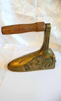 an antique brass colored hammer with wooden handle on white fabric covered background, closeup