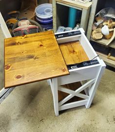 a wooden table sitting on top of a floor next to a pile of wood planks