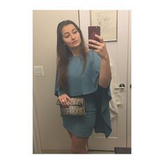 a woman taking a selfie with her cell phone in front of a mirror wearing a blue dress