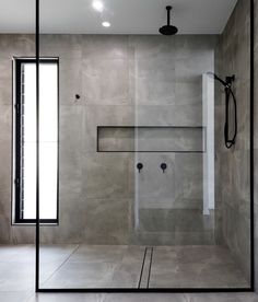 a bathroom with a glass shower door and tiled walls