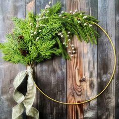 a wreath with white flowers and greenery is hanging on a wooden wall next to a ribbon