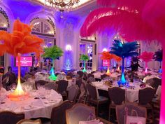 an indoor banquet hall with tables and chairs decorated in pink, orange, and blue colors