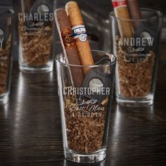 four shot glasses with cigars in them sitting on a table next to each other