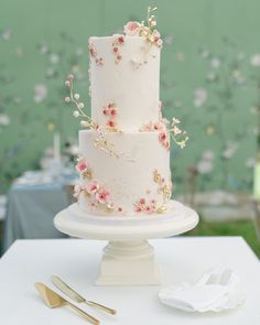 a wedding cake with pink flowers on it sitting on top of a white tablecloth