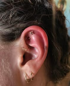 a close up of a person's ear with gold hoops on the side