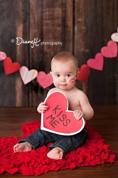 a baby is holding a heart shaped sign