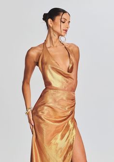 Dare to shine in our Cleo Dress. This cowl neck halter dress features a pleated detail at the hip and an ultra side slit. Shown here in Nude Glitter. 72% Silk, 28% Metallic Made in China Model is 5'10" wearing size S Style No. PF23-7060 Pre-draped Cowl Neck Dress For Gala, Pre-draped Evening Dress With Cowl Back For Party, Glamorous Fitted Dress With Cowl Back, Chic Maxi Dress With Cowl Back For Party, Evening Dresses With Ruched Bodice And Halter Neck, Pre-draped Halter Neck Party Maxi Dress, Glamorous Summer Dress With Cowl Neck, Summer Evening Halter Dress With Cowl Back, Ruched Draped Halter Dress For Evening