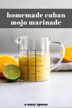 a measuring cup filled with orange juice next to sliced lemons and lime wedges