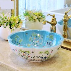 a blue and white bowl sink sitting on top of a counter next to a mirror