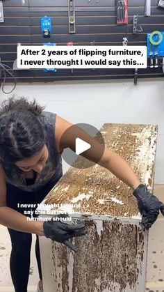 a woman in black shirt and gloves working on a piece of wood with brown paint