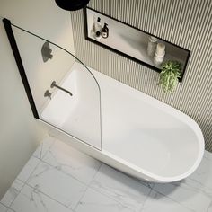 a white bath tub sitting on top of a bathroom floor next to a sink and mirror