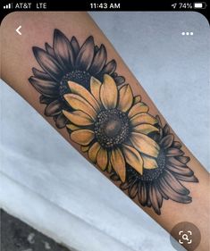 a sunflower tattoo on the arm with black and yellow flowers in it's center