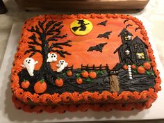 a decorated cake with pumpkins and ghostes on it's side, sitting on a table