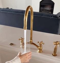 a person is washing their hands under a faucet in a bathroom with gold fixtures