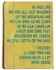 a wooden sign that says we are all just walking up the mountain and we can sing as we climb