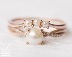 two rings with pearls on them sitting on a white surface