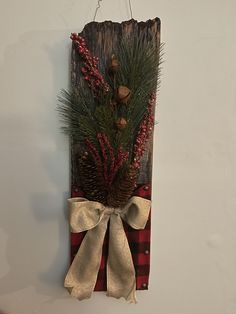 a wooden sign with pine cones and berries hanging from it's side on a wall