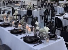 tables set up with black and white linens for an outdoor wedding reception at dusk