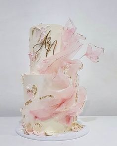 a three tiered cake with pink and white frosting