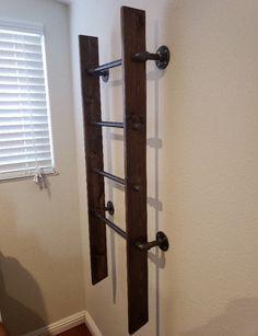 a wall mounted coat rack made out of wooden planks and metal bars, in the corner of a room