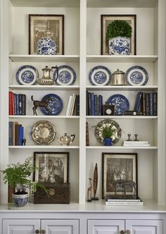 a white bookcase with blue and white plates on it