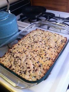 a casserole dish is sitting on the stove next to a blue pan with food in it