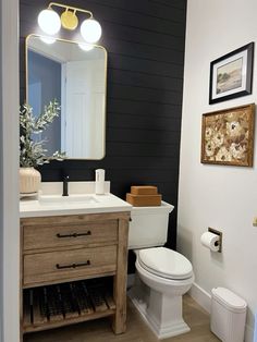 a white toilet sitting next to a wooden cabinet in a bathroom under a large mirror