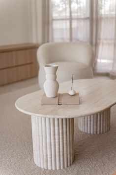 a white vase sitting on top of a table in front of a couch and chair