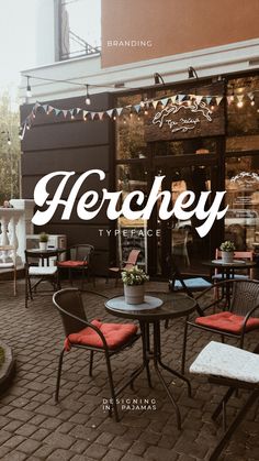 there is a sign that says herchely on the side of a building with chairs and tables outside