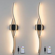 two wall lights that are next to each other with remotes on the floor below them